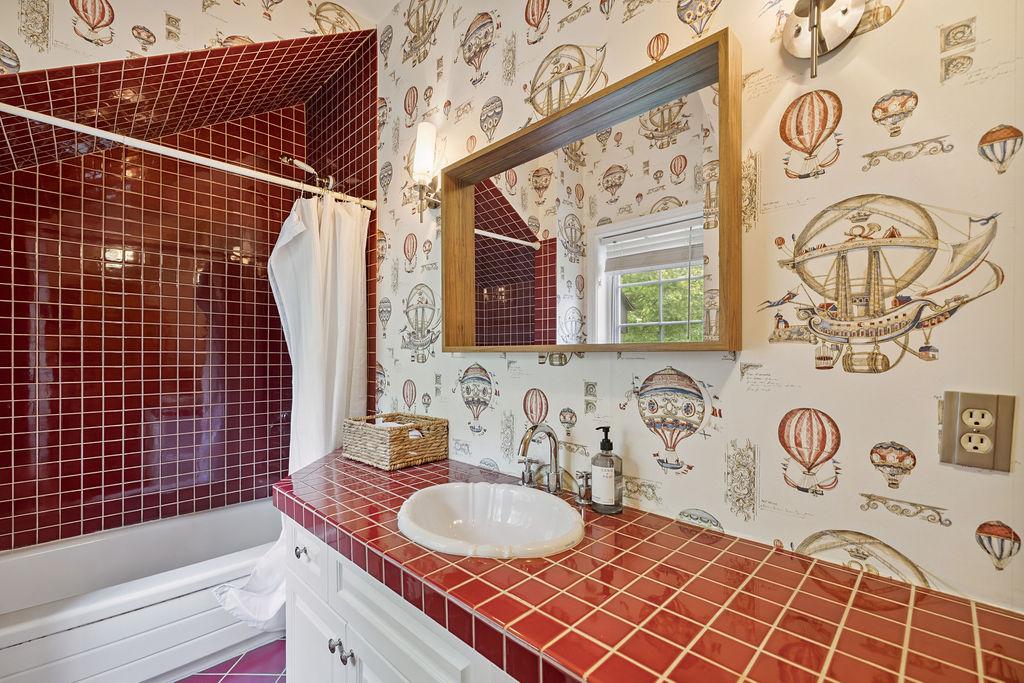 A red and white bathroom with a red tiled shower
