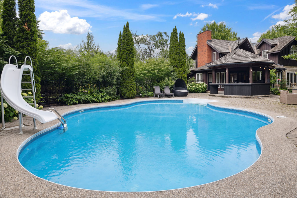 A round backyard pool surrounded by trees