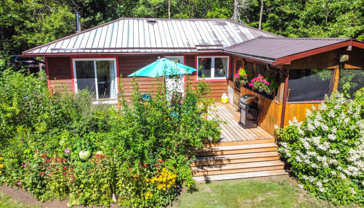 A wood cottage with a teal umbrella on the back deck
