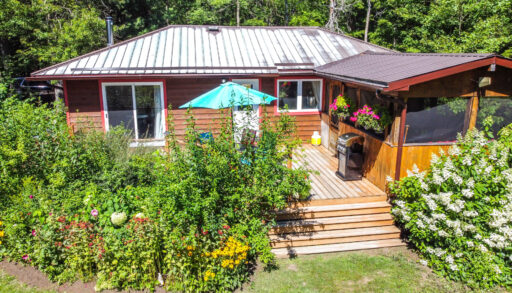 A wood cottage with a teal umbrella on the back deck