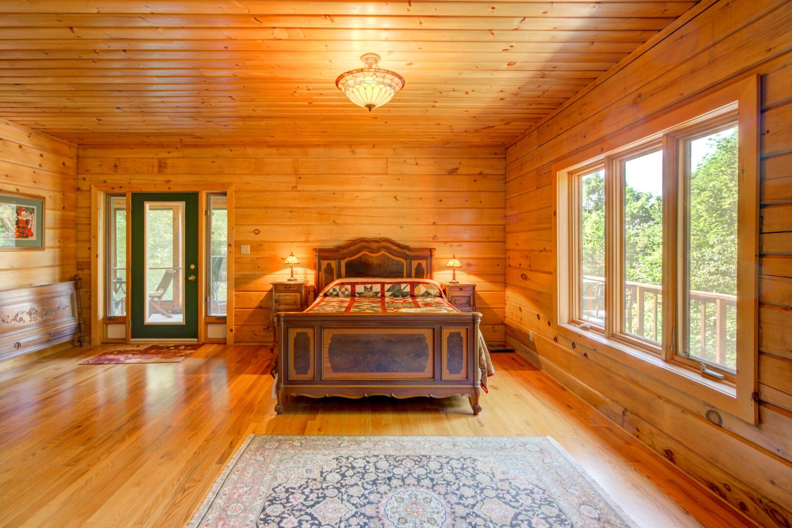 A brown wood bed with a red bedspread in a wood paneled room