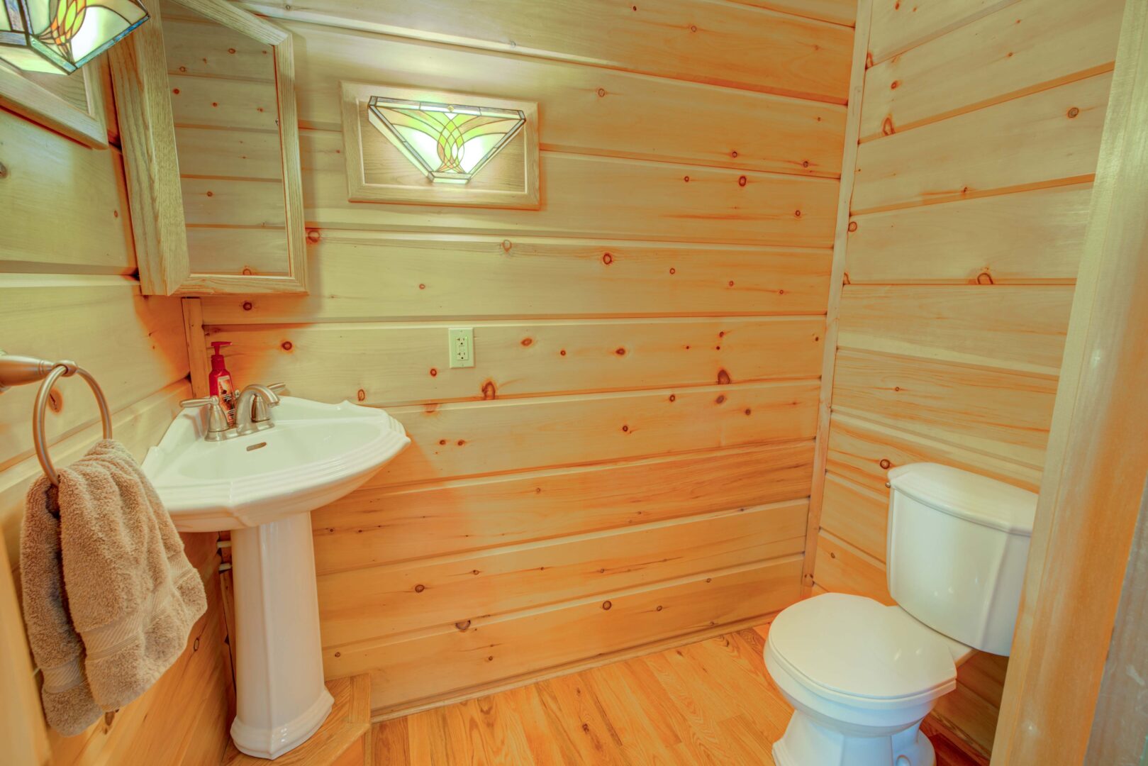 A wood paneled bathroom with a white ceramic vanity