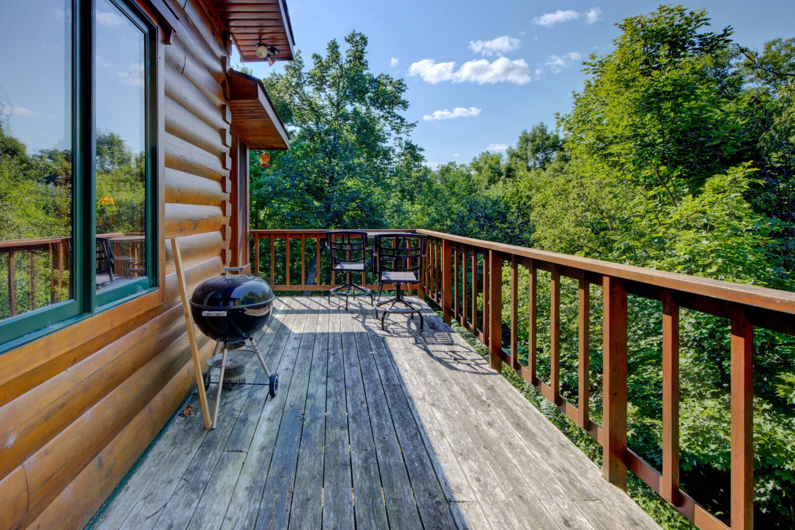 A wood deck along the side of a log cabin