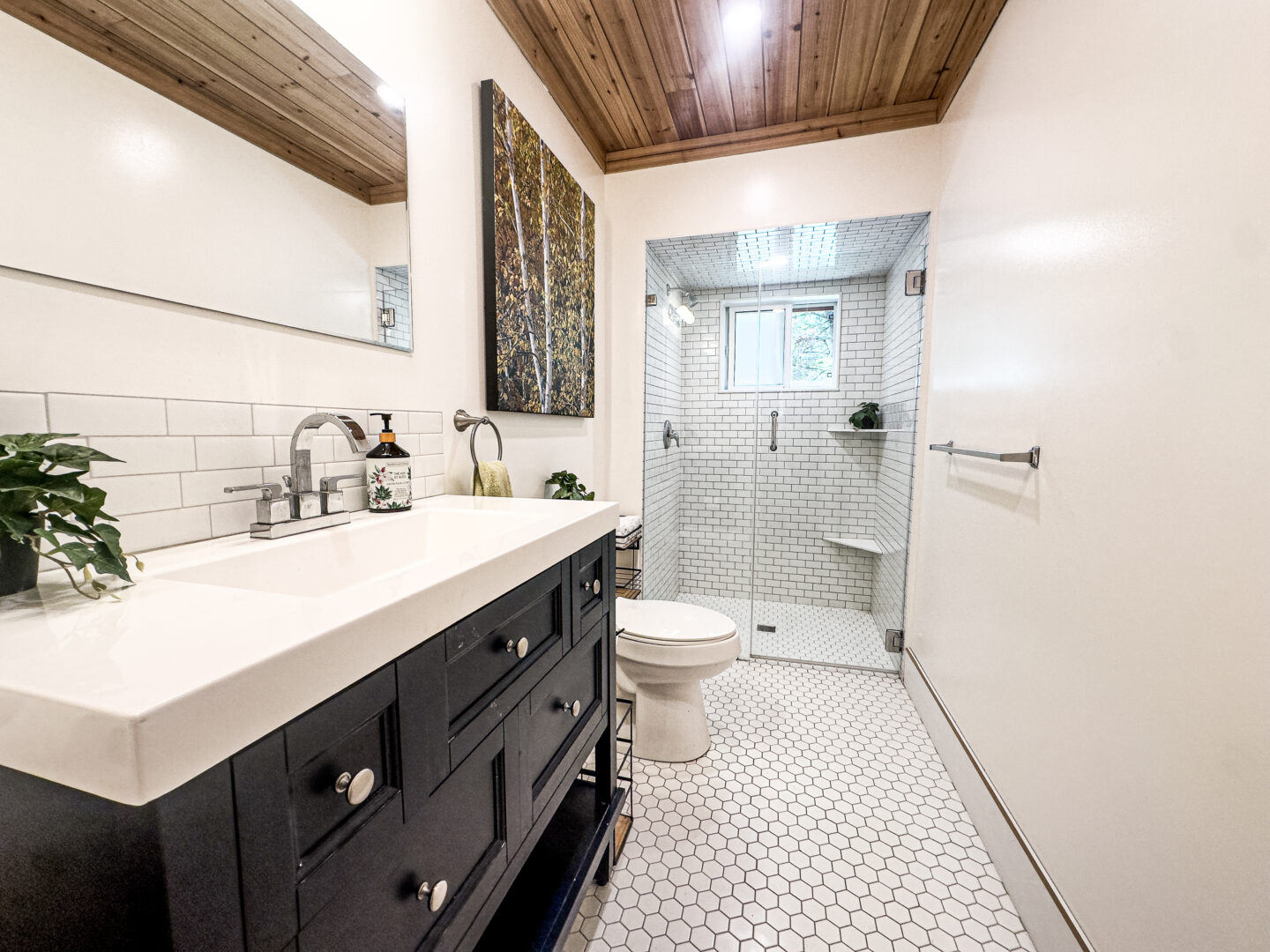 A white bedroom with a glass walk-in shower and a navy blue vanity