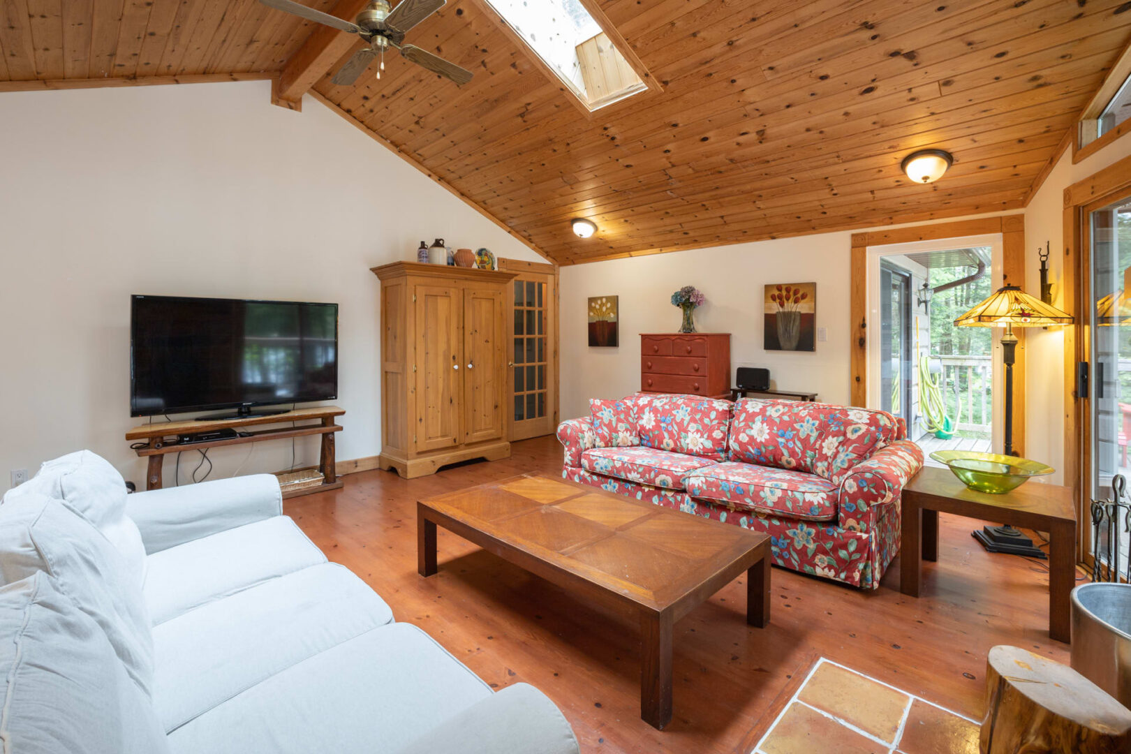 A white couch faces a red floral couch in a cottage living room