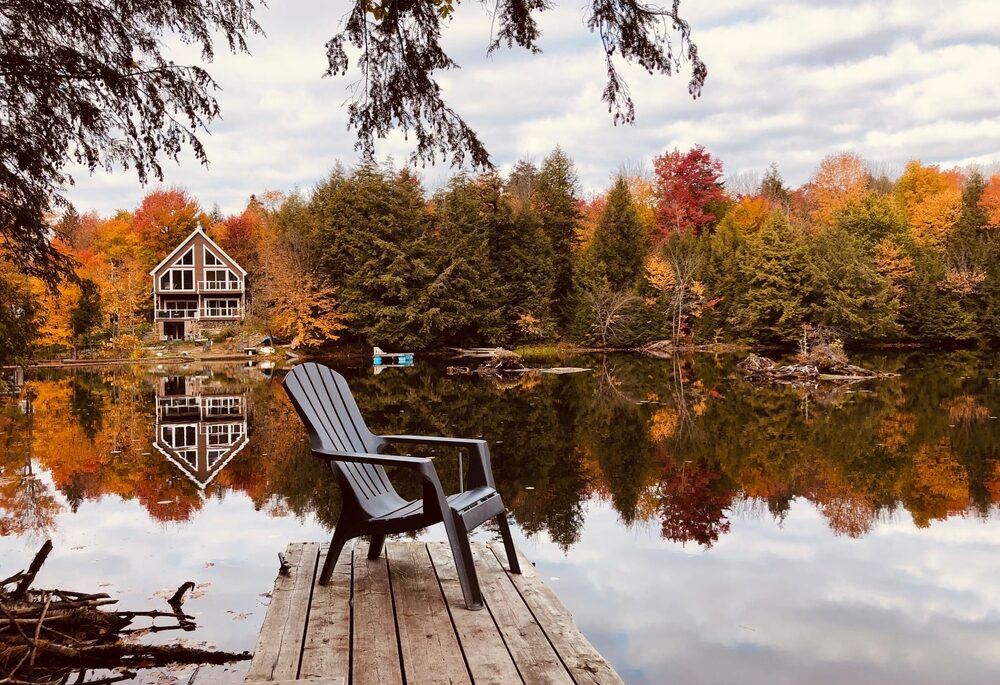 Dock by a calm lake surrounded by trees during autumn/fall