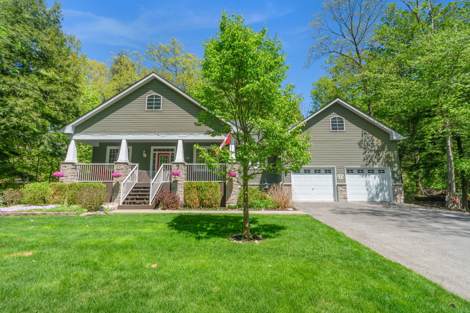 A green paneled house on a grassy property