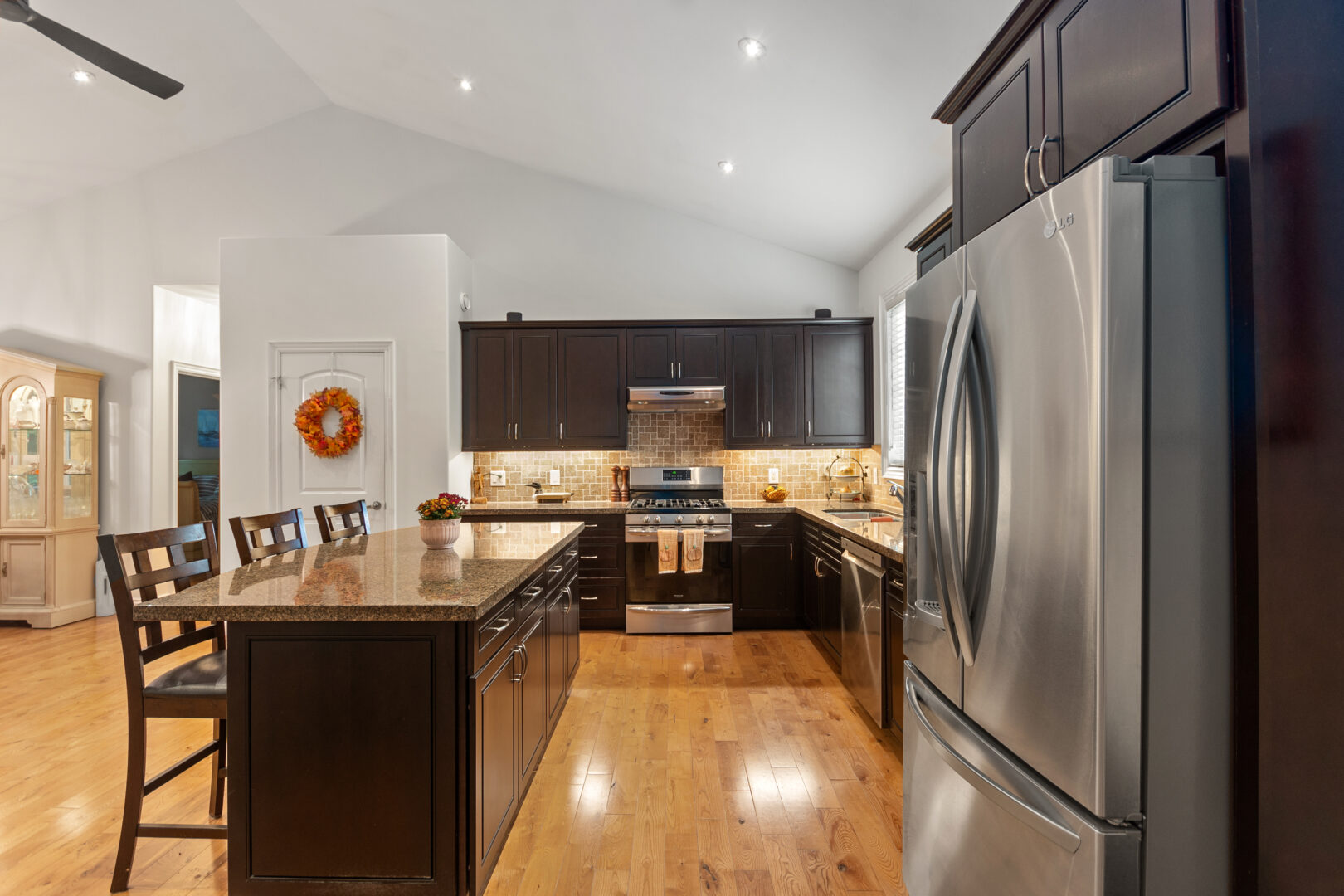 A dark wood kitchen island across from the silver fridge