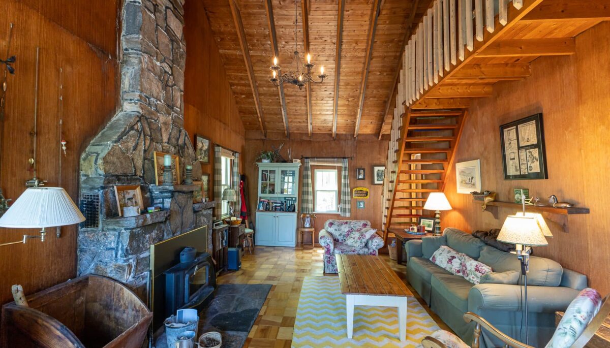 A couch faces a wood coffee table and a granite fireplace in a wood living room