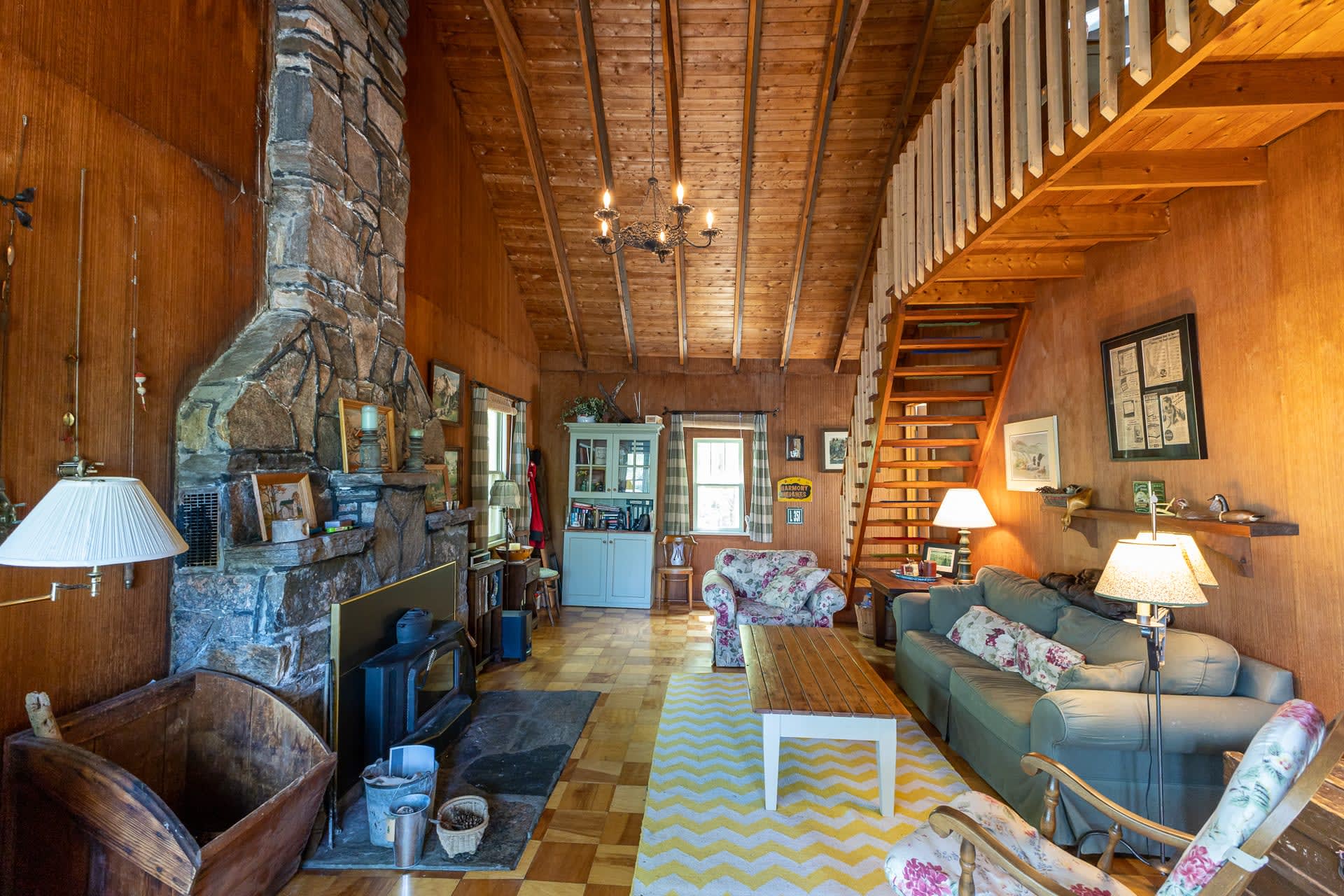A couch faces a wood coffee table and a granite fireplace in a wood living room