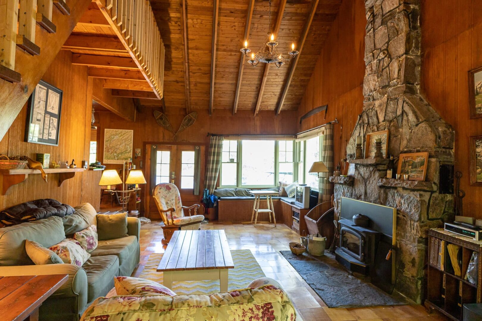 A couch faces a wood coffee table and a granite fireplace in a wood living room