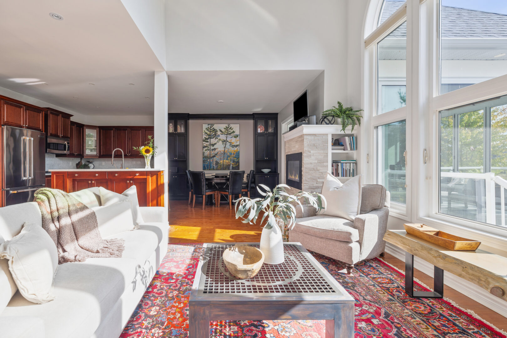 A white living area with a red rug. the white couch faces large windows