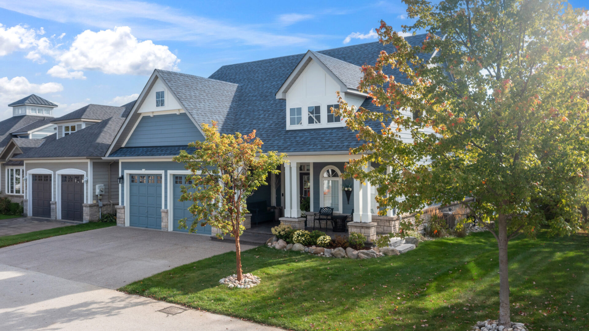 A grey and white cottage with a grassy lawn