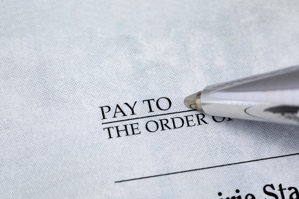 Writing check with pen. Banking, paying bills, and financial fraud concept