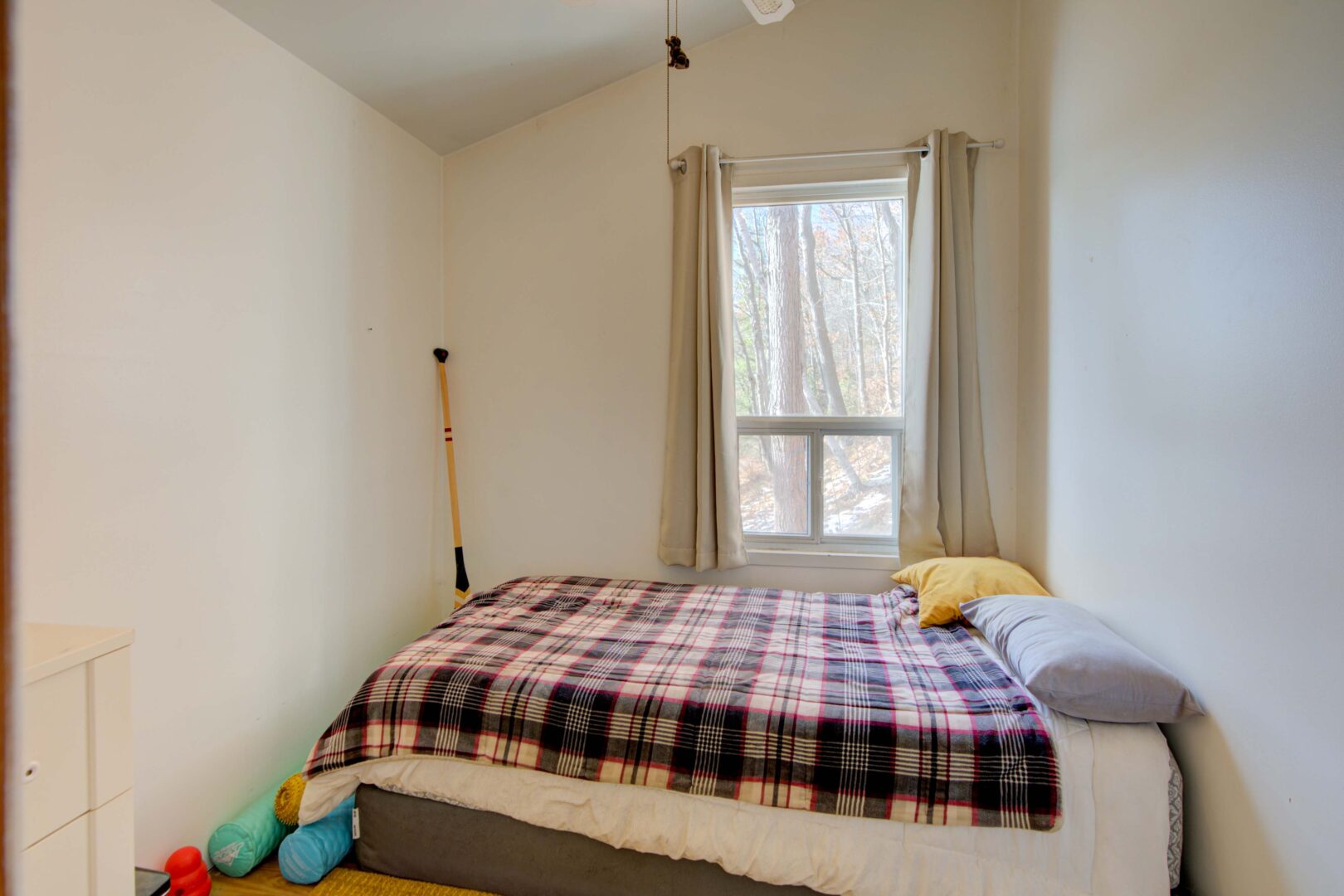 A bed with a plaid bedspread in a white bedroom