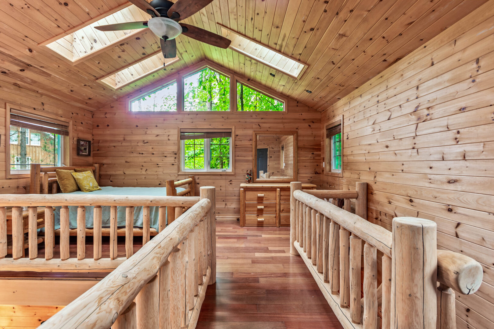 A narrow hall with wood railings lead into a wood loft area