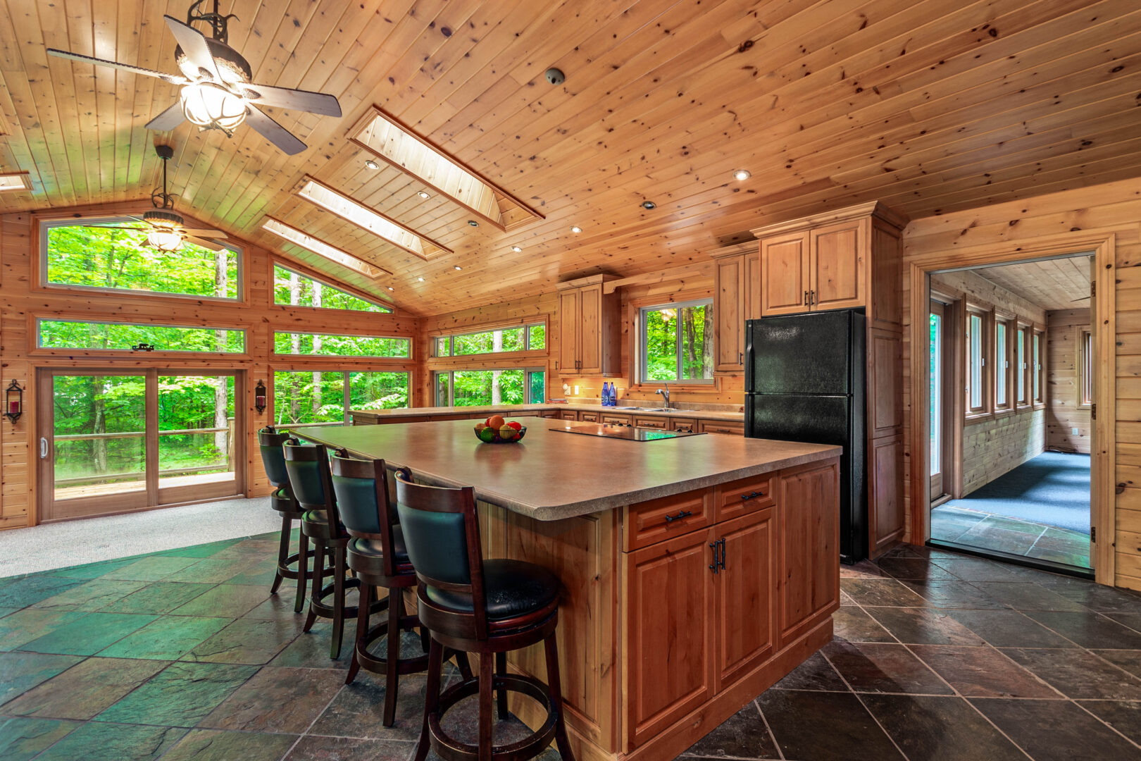 A wood kitchen with an oversized kitchen island and black bar stools