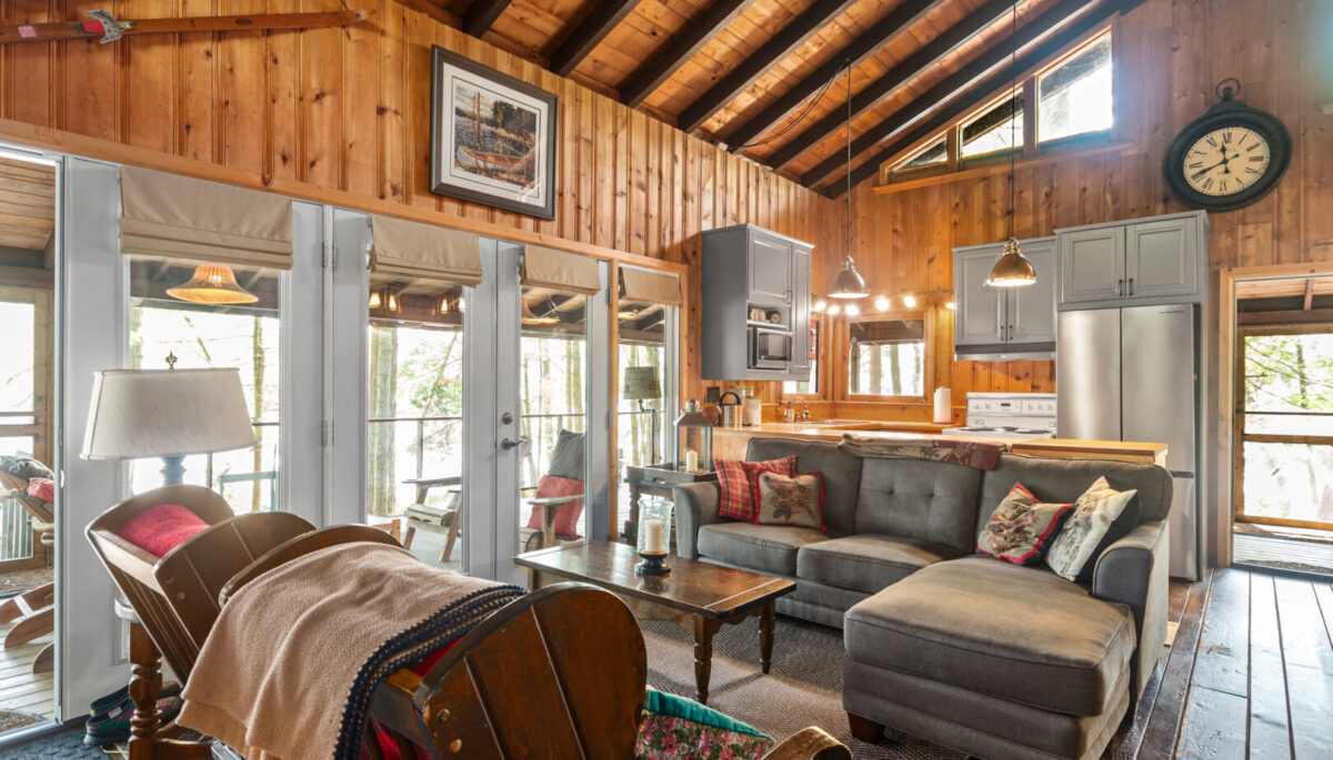 A grey couch faces a gred loveseat in a wood cottage