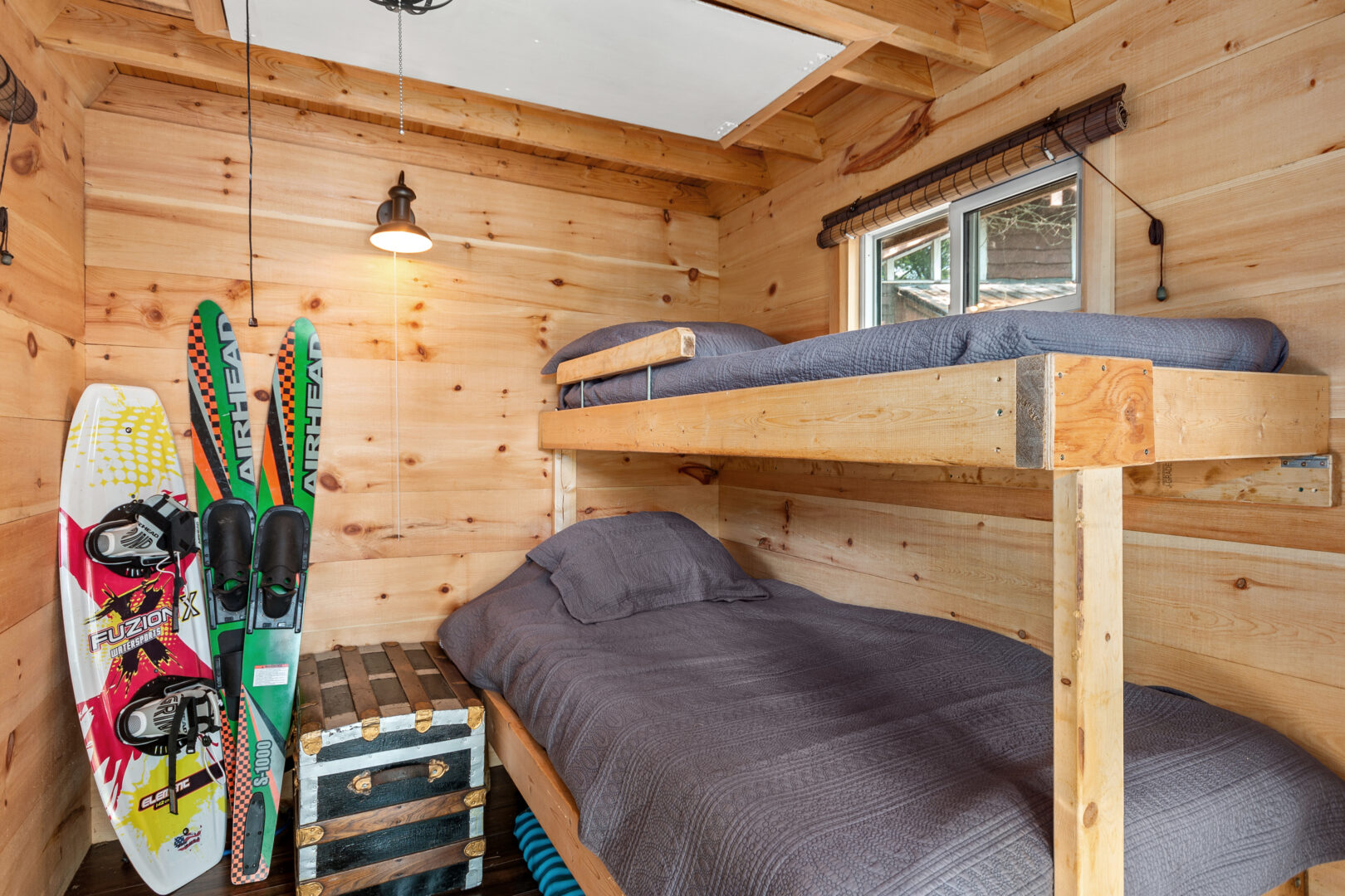Bunk beds with grey covers in a light wood paneled room