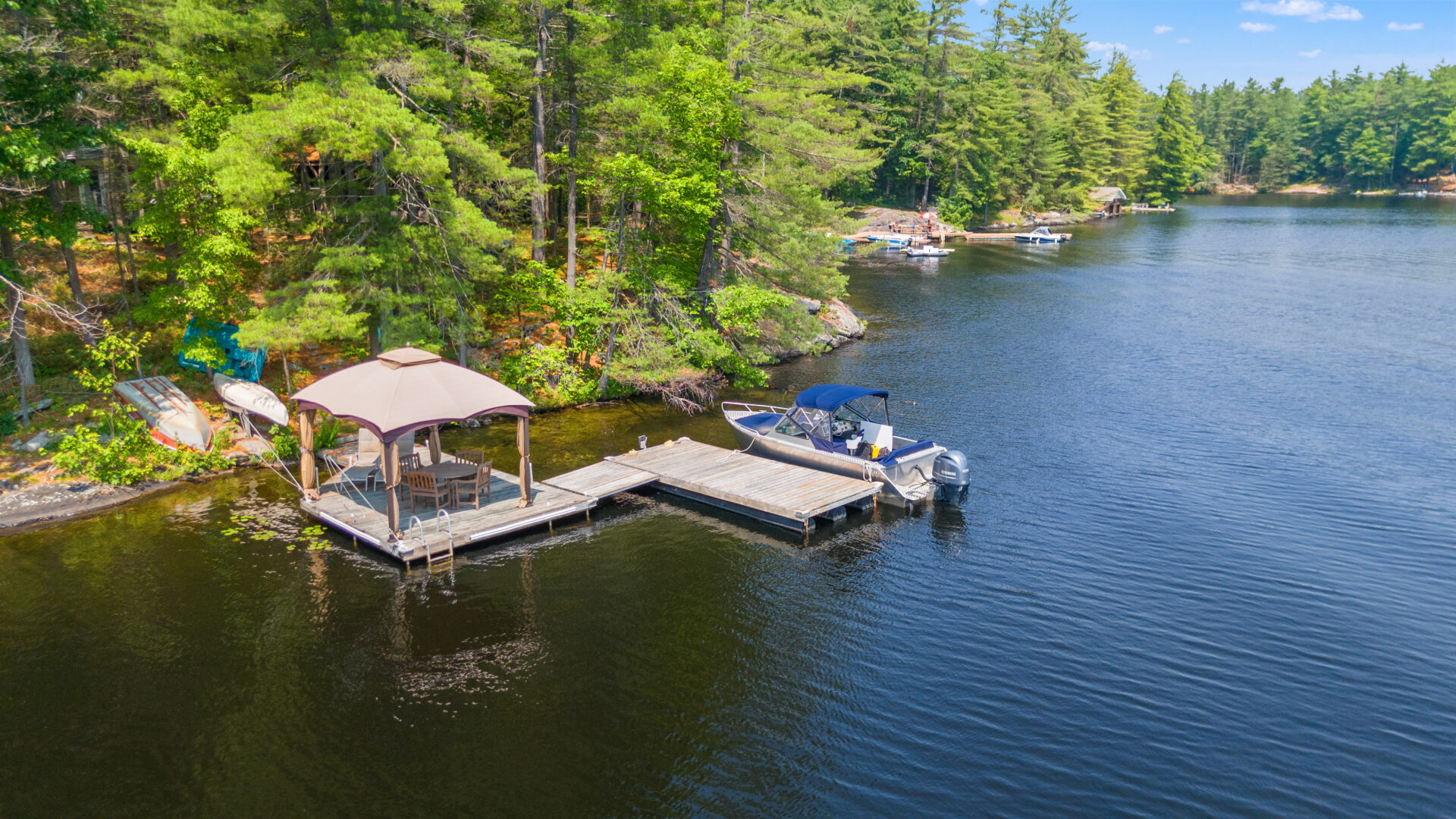 An L-shaped dock with a pergola and a boat parked along the side