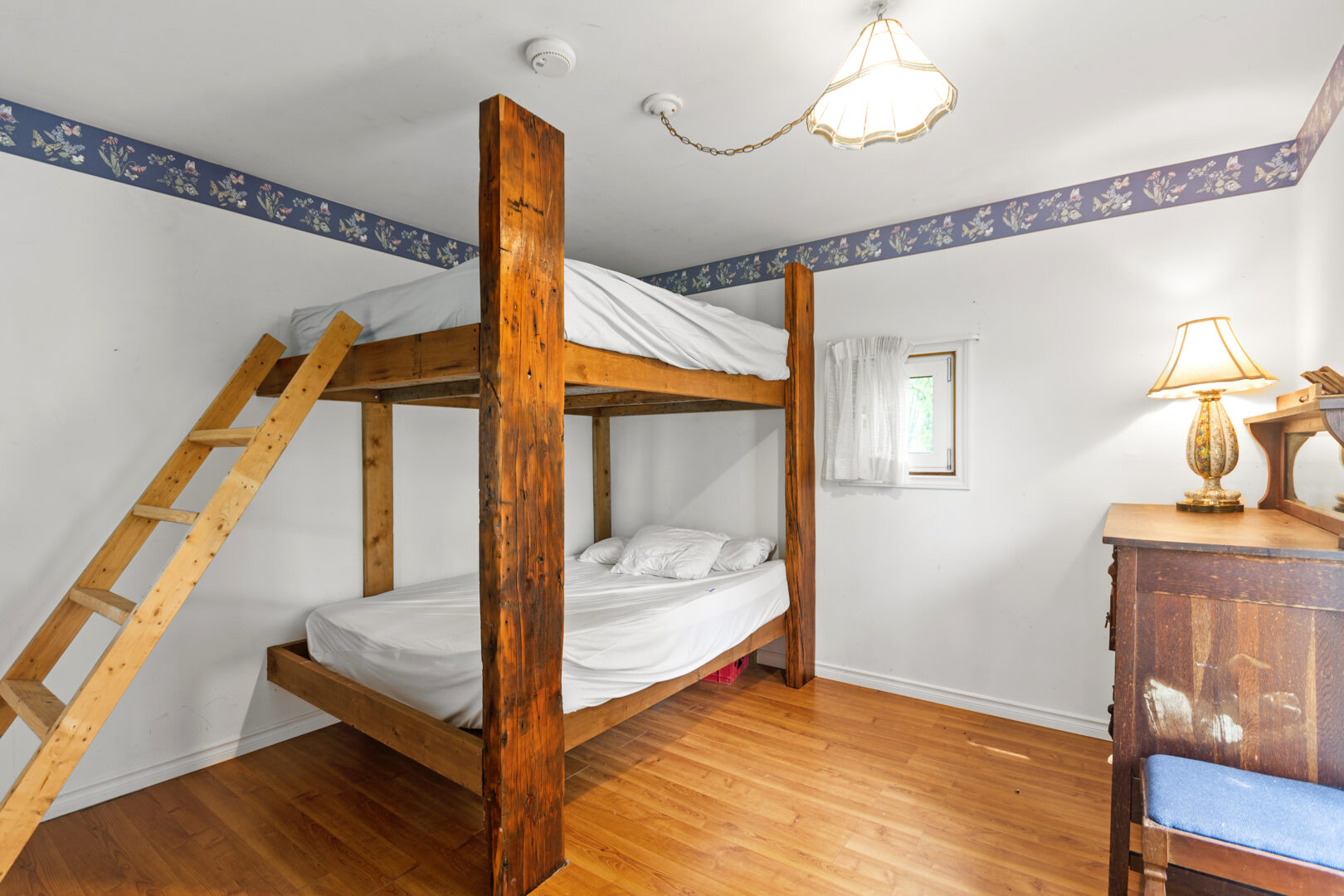 Wood bunk beds with white bedding in a white bedroom