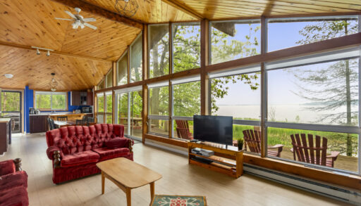Red couches face a TV in bright living room with cathedral ceilings and floor-to-ceiling windows