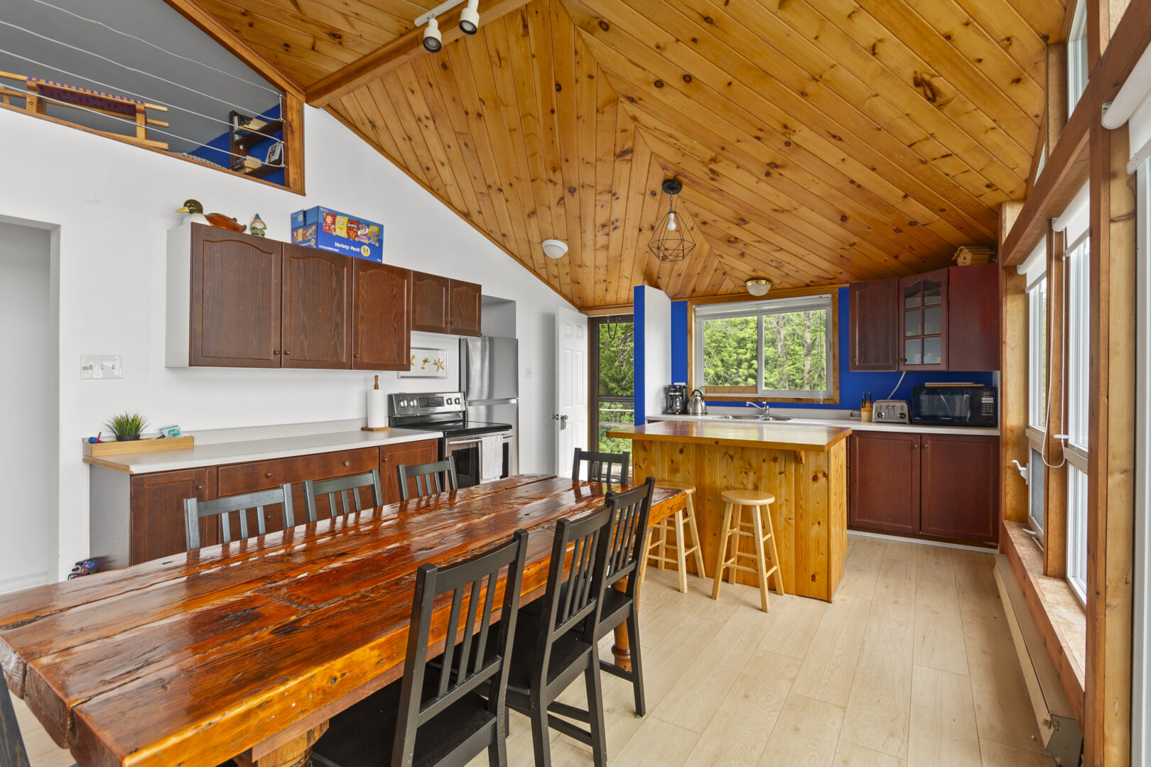 A rectangular wood dining table is adjacent to an open-concept kitchen