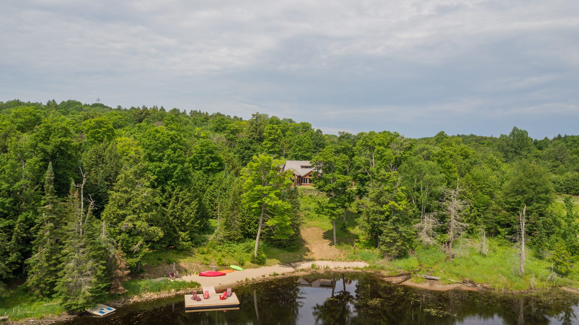 A log cabin is nestled in the trees of a waterfront property