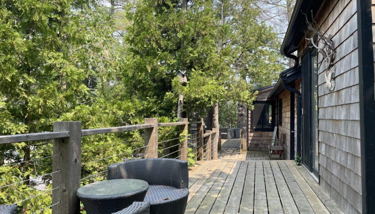 A wood deck with a small sitting area outside a wood cabin