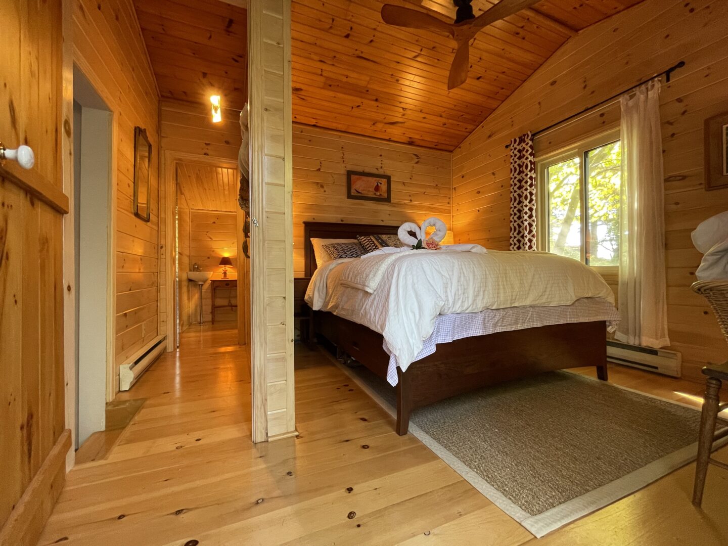 A white bed on a dark wood bed frame in a wood paneled room