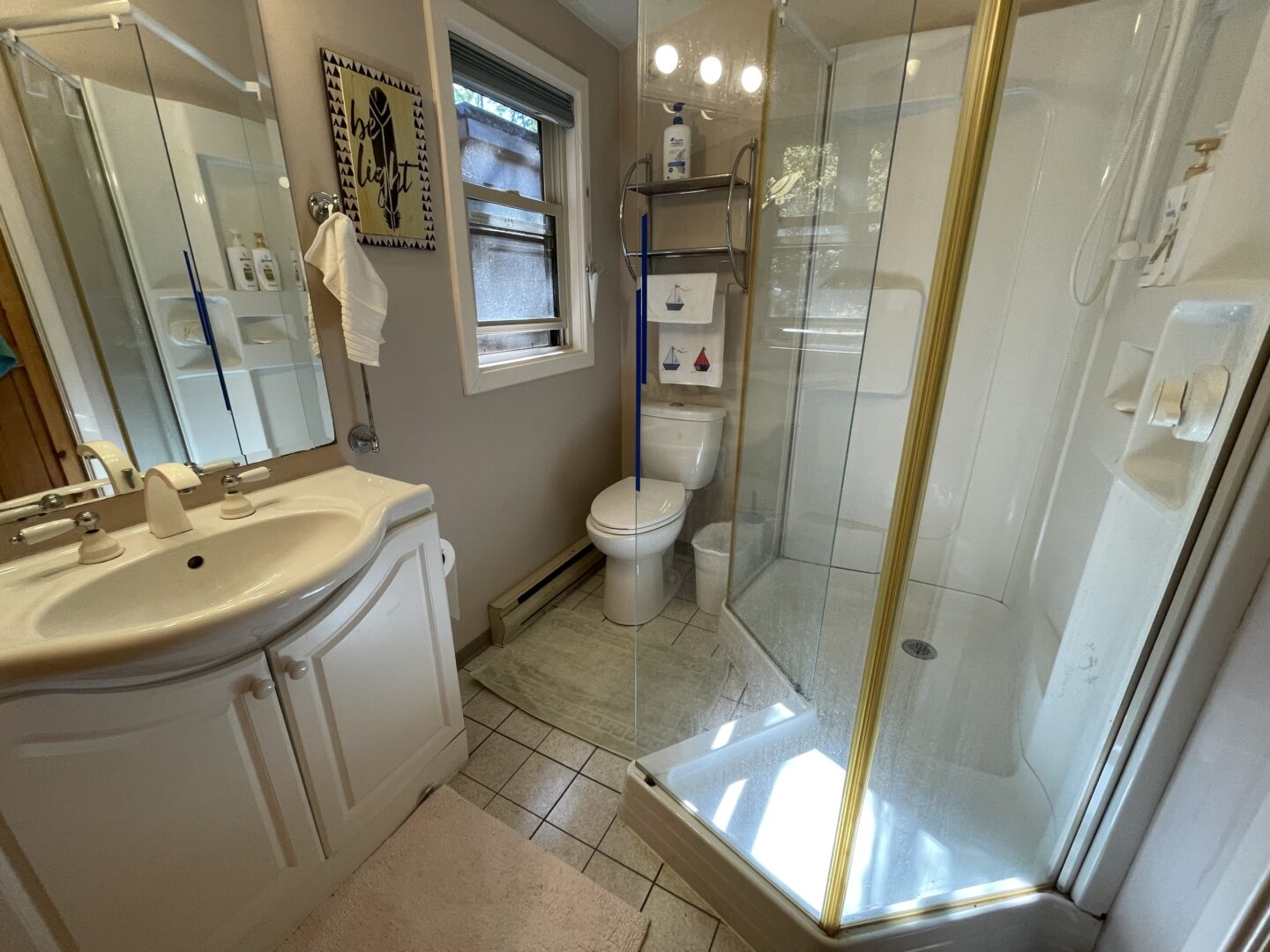 A beige bathroom with a glass walk-in shower and a white vanity