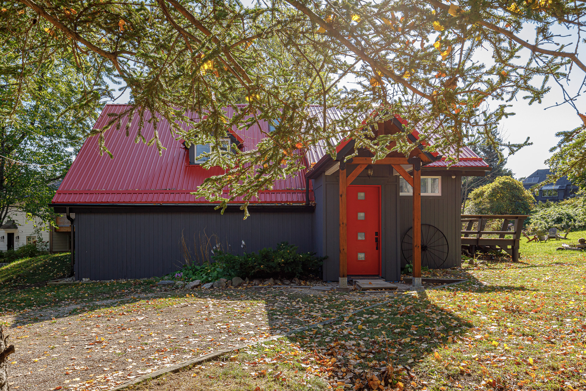 A black cottage with a red roof and red front door