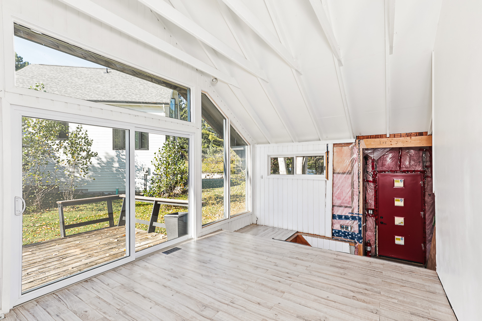 A white living area with vaulted ceilings and an unfinished entryway