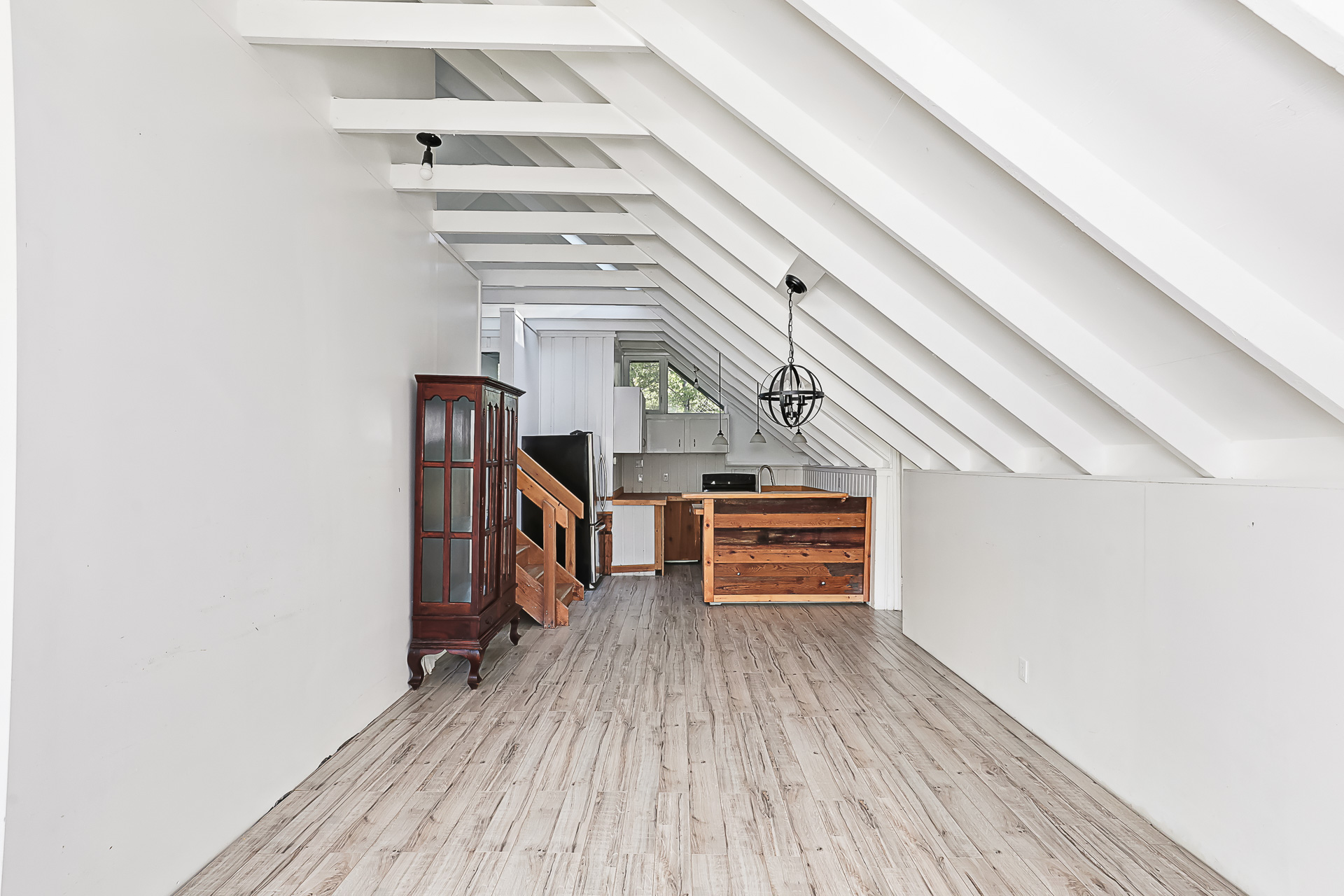 A white living area with a wood kitchen area tucked in the back