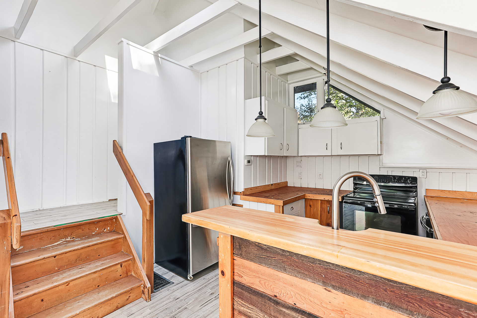 A white kitchen with sloped ceilings and wood cabinetry