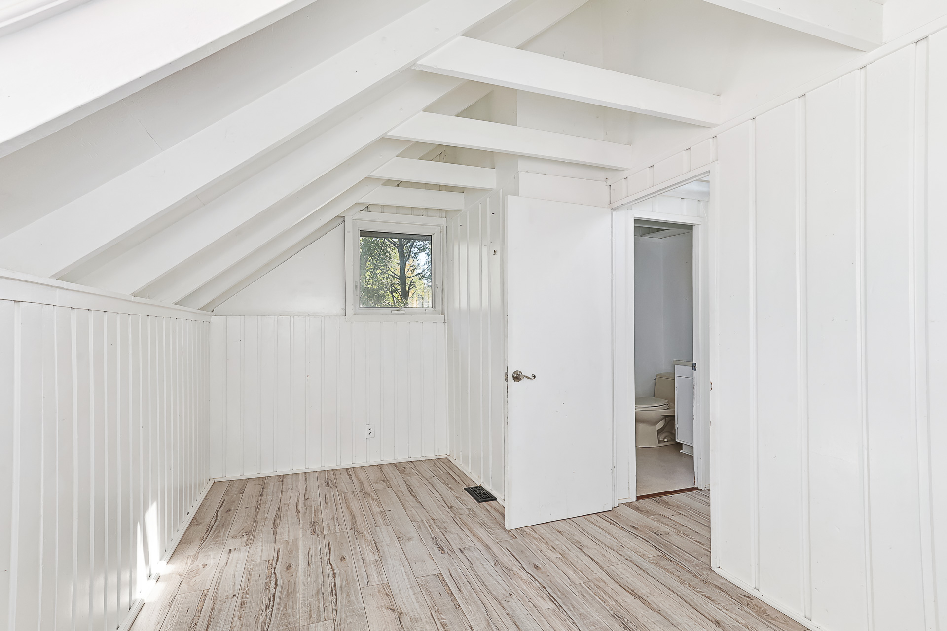 A white bedroom with sloped ceilings and an ensuite bathroom