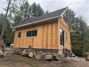 A wood cabin is propped up by stones