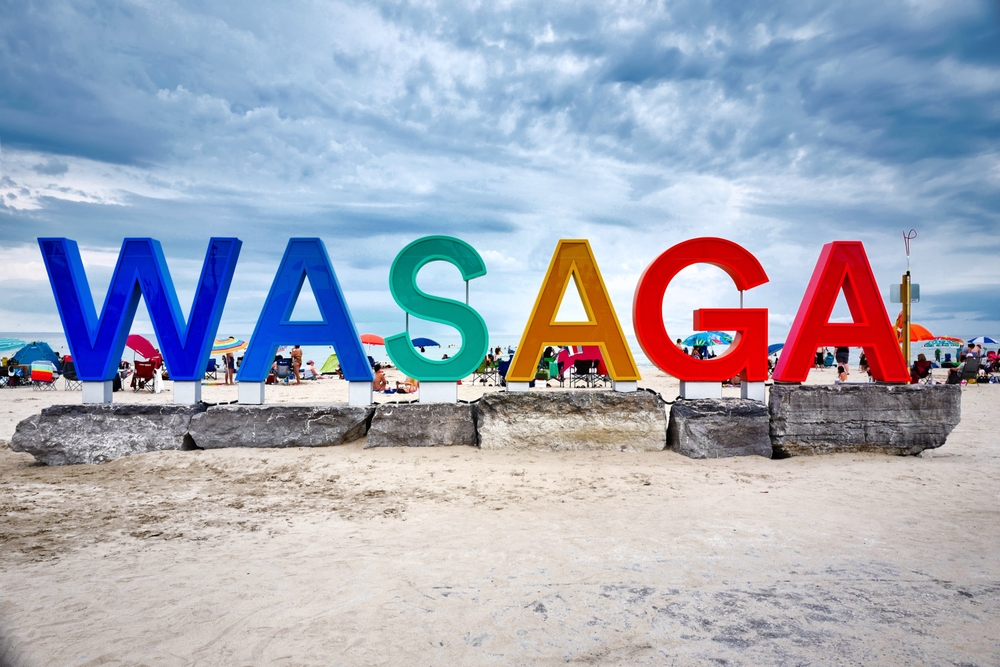 Colourful giant Wasaga beach sign sitting on big rocks at Ontario famous popular summer travel destination Wasaga beach near Georgian Bay. Its long, sandy beach lies on Nottawasaga Bay.
