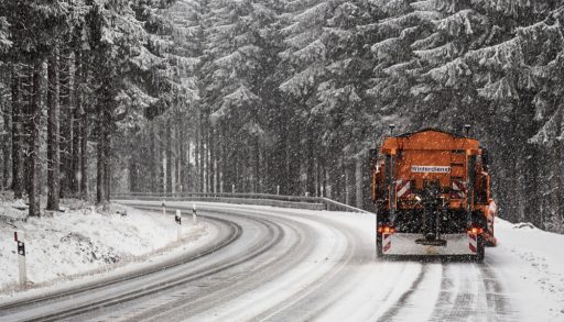 An orange truck clearing a road and applying salt