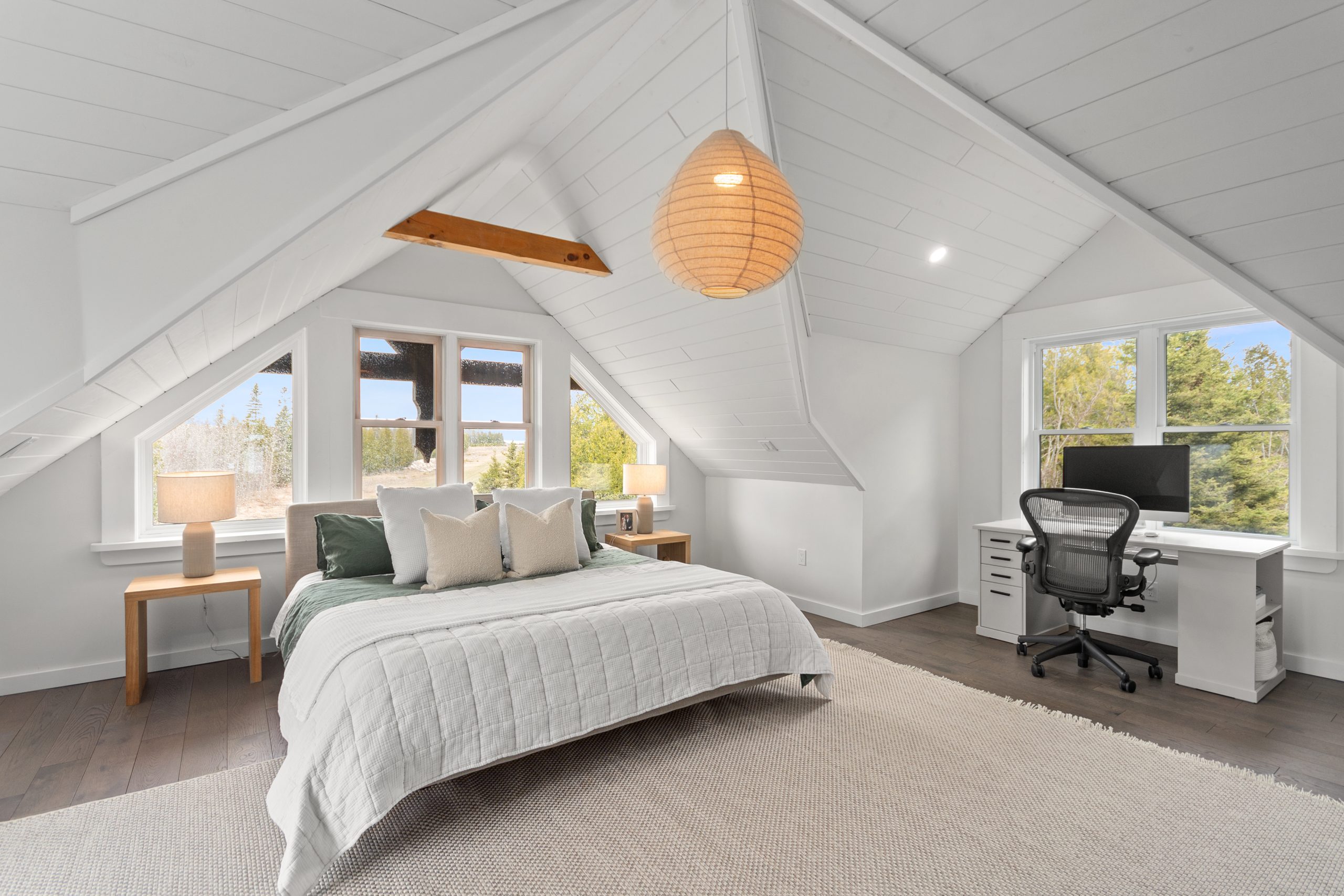 Bedroom with a vaulted ceiling, large windows, a desk workspace, and a bed set beneath the sloped roofline.