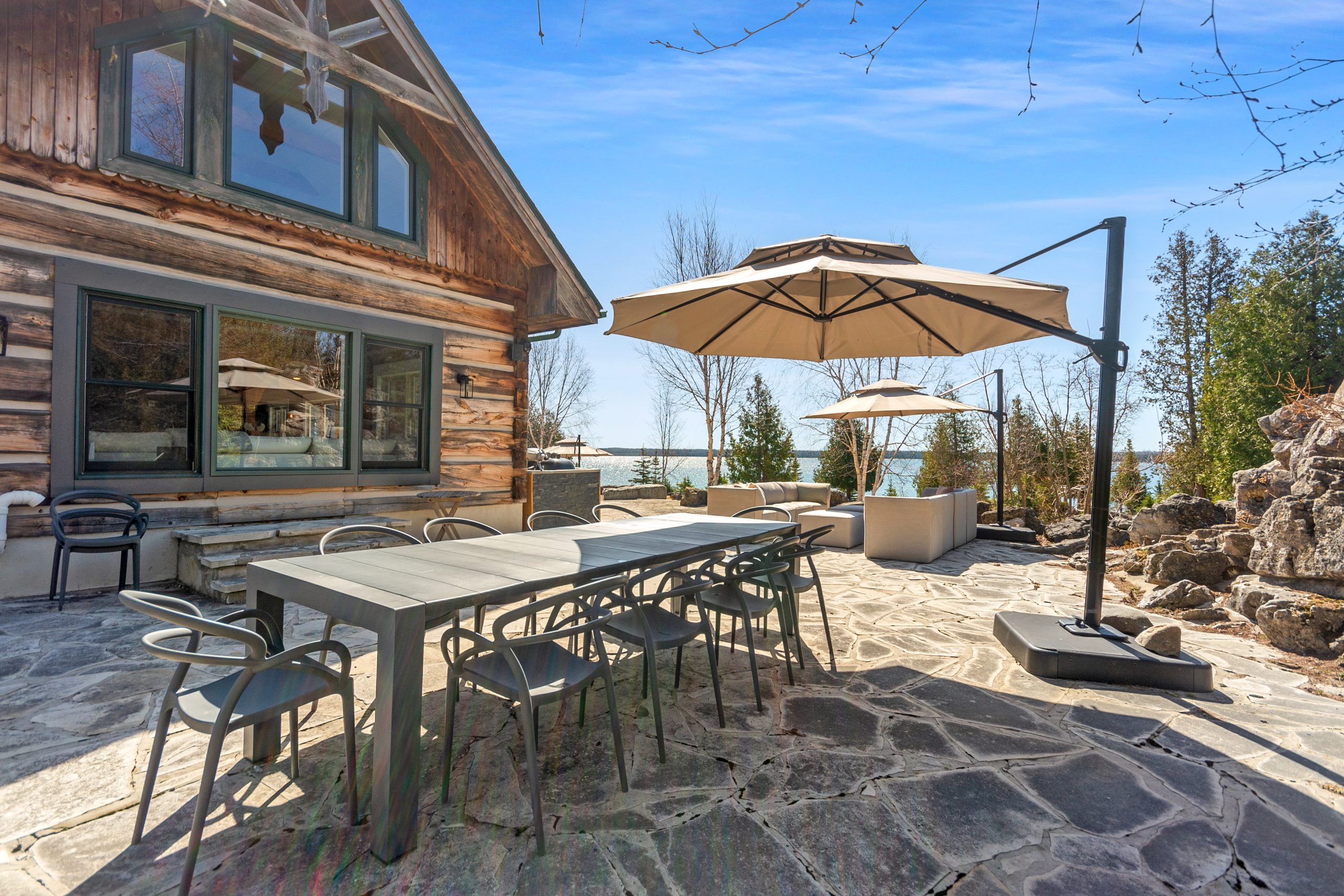 Outdoor stone patio with a dining table and umbrella set alongside the lodge exterior.