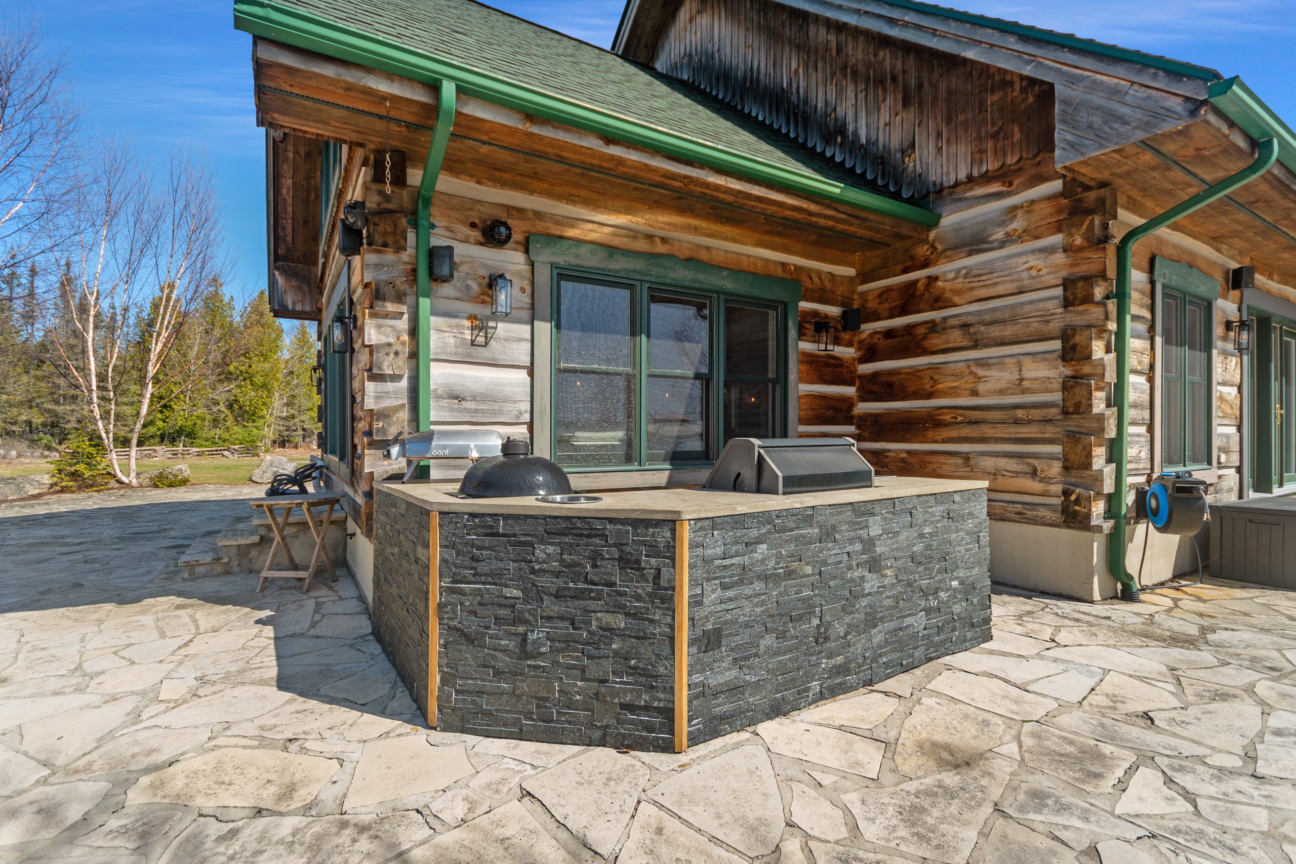 Stone patio area with a built-in barbecue and outdoor prep space beside the lodge.